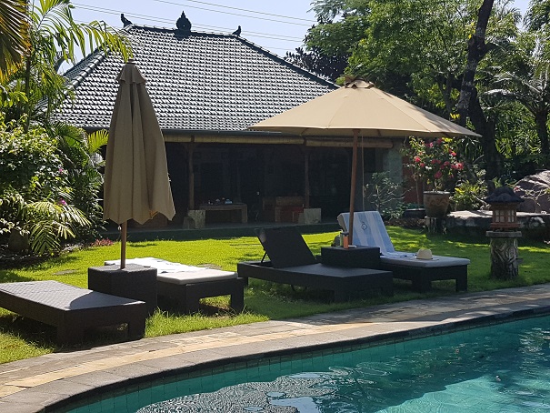 ligstoelen aan het zwembad op achtertergrond huisje